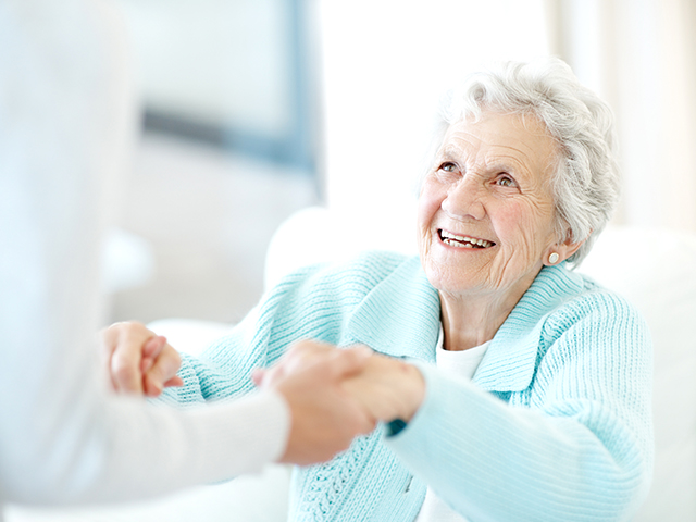 image of a happy female senior reaching out her hands to her caregiver.