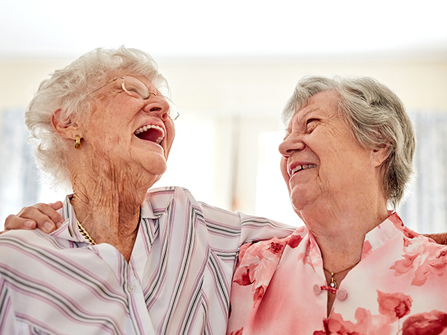 image of two happy elderly women embracing each other at home
